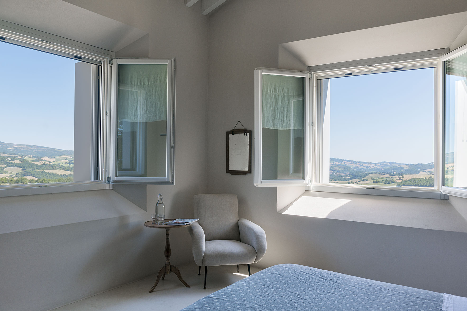 Bedroom with armchair and two windows of Malatetsa Maison de Charme in the marche hills Photographer Maria Teresa Furnari