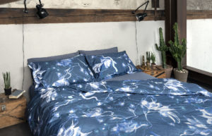 Bedroom with blue and white sheets and grey blanket of Diesel Home Linen Collection Photographer Maria Teresa Furnari