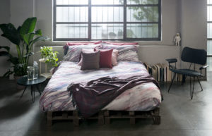 Bedroom with pink sheets and a violet blanket of Diesel Home Linen Collection Photographer Maria Teresa Furnari